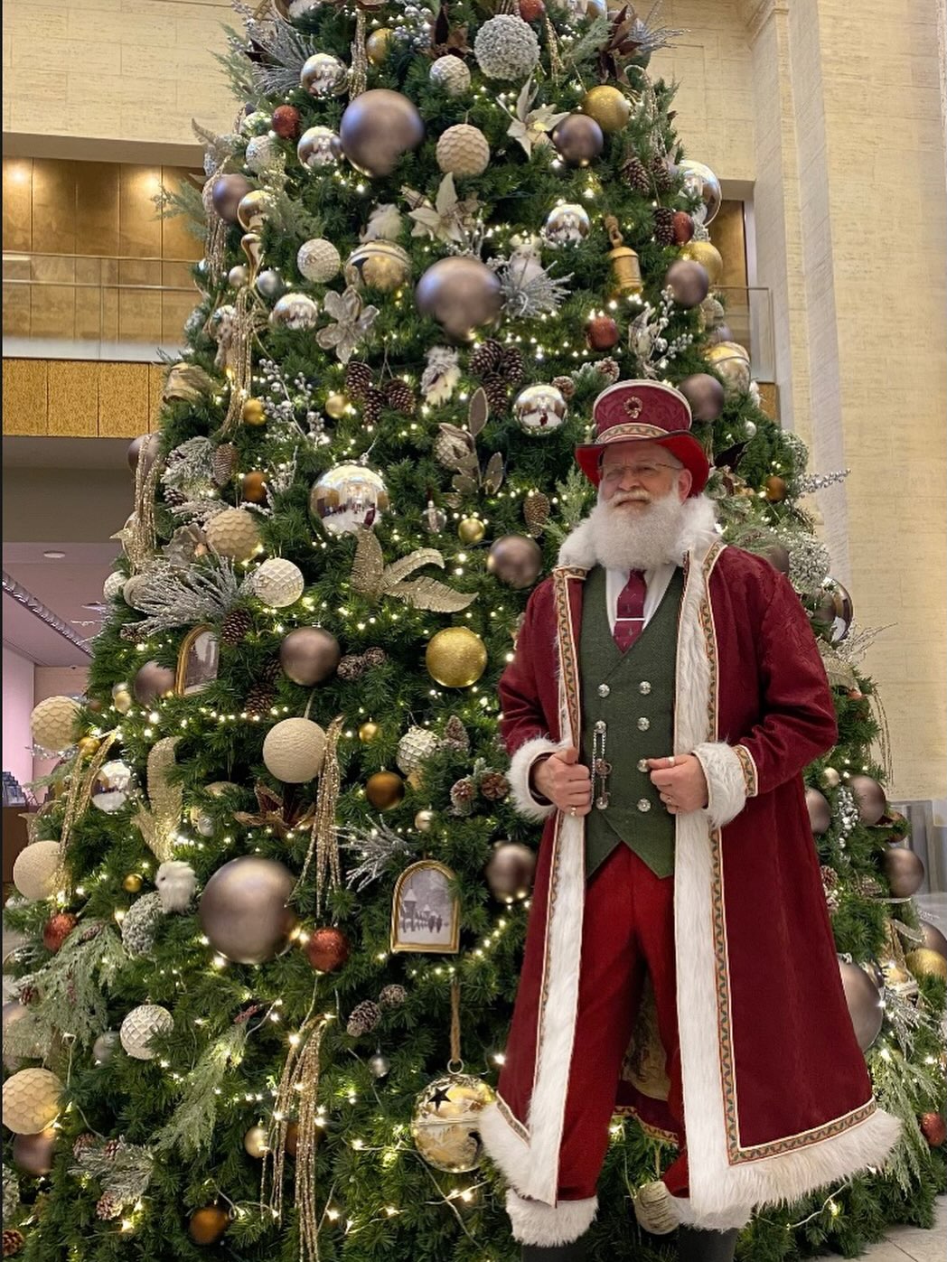 Saint Rick standing beside a fully decorated Christmas tree
